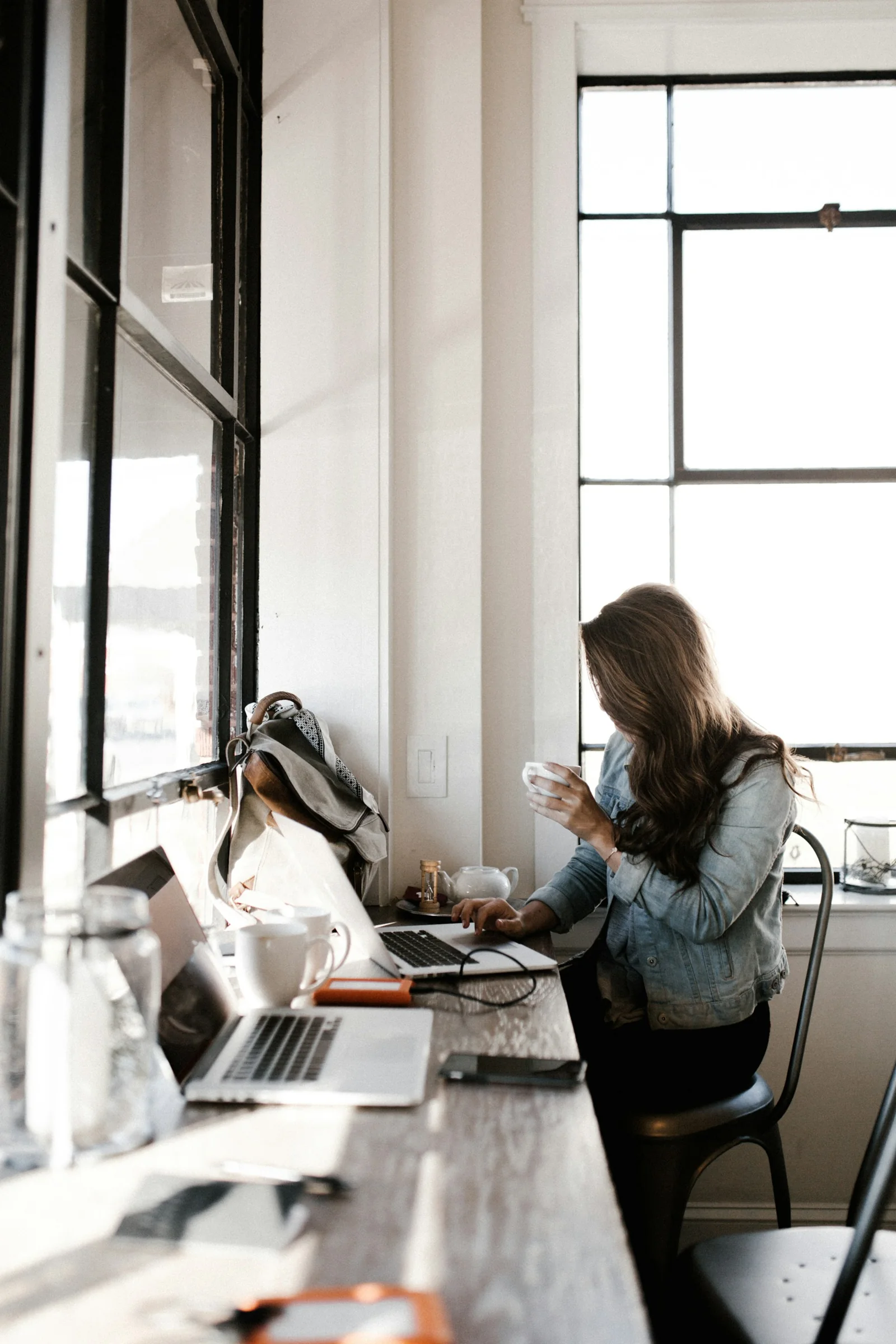 A woman working on a laptop beside a café window